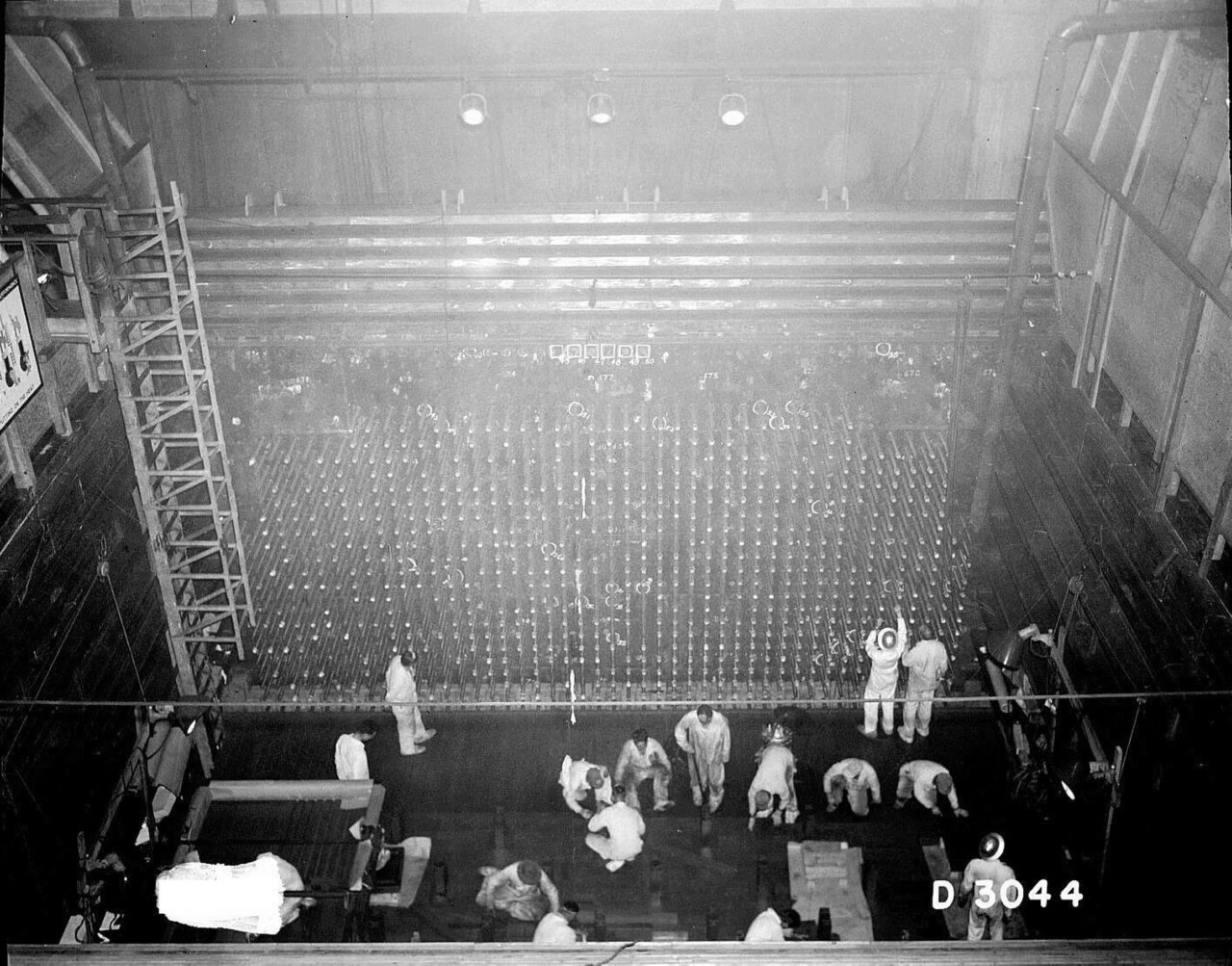 Workers in protective clothing load slugs into the reactor face