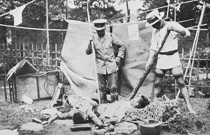 Police and a civilian stand over bodies of victims in a ruined garden