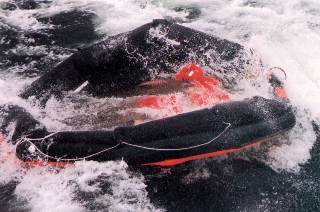 A life raft floats empty in heavy seas