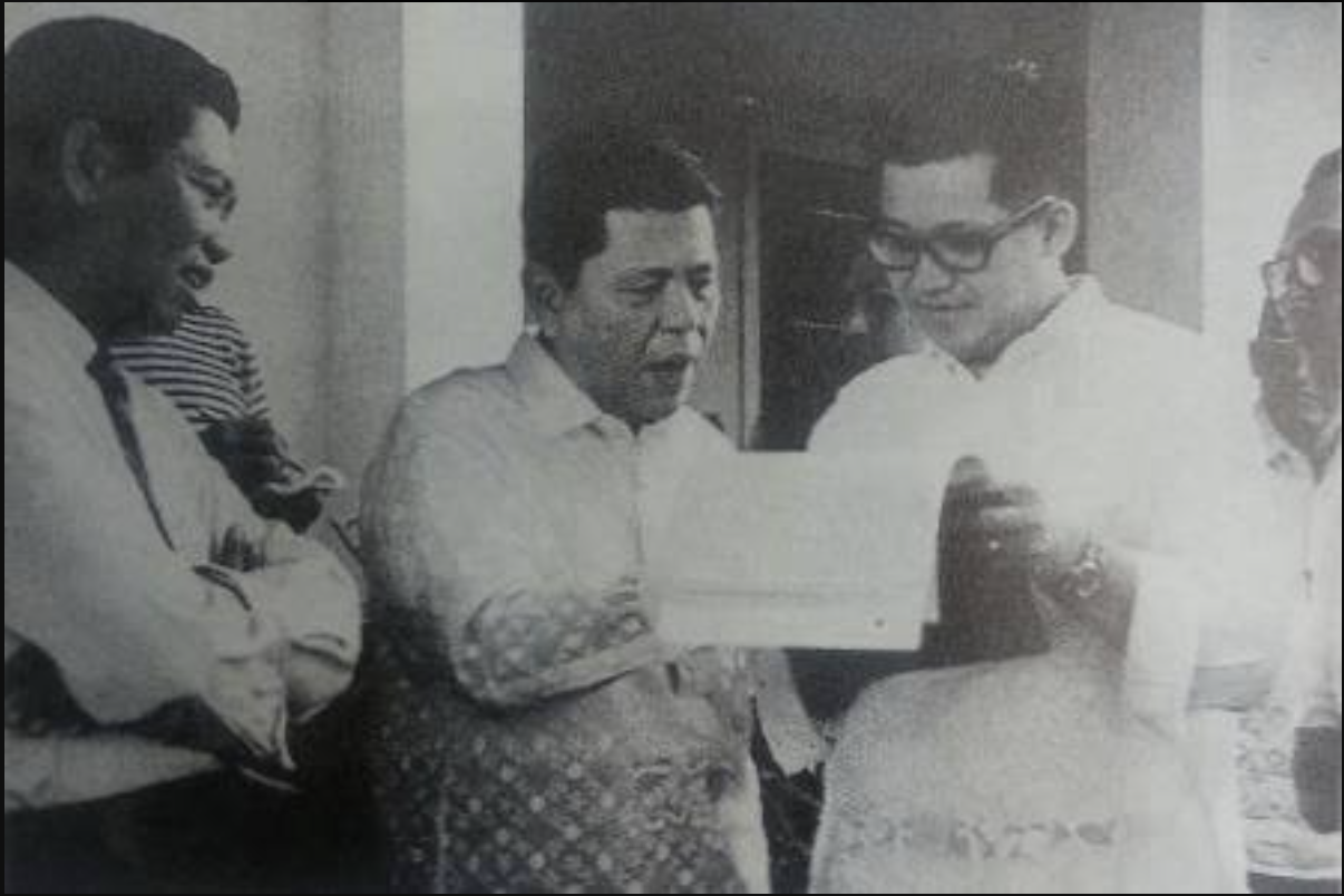 Opposition leader Benigno Aquino Jr. reads a document with companions before boarding