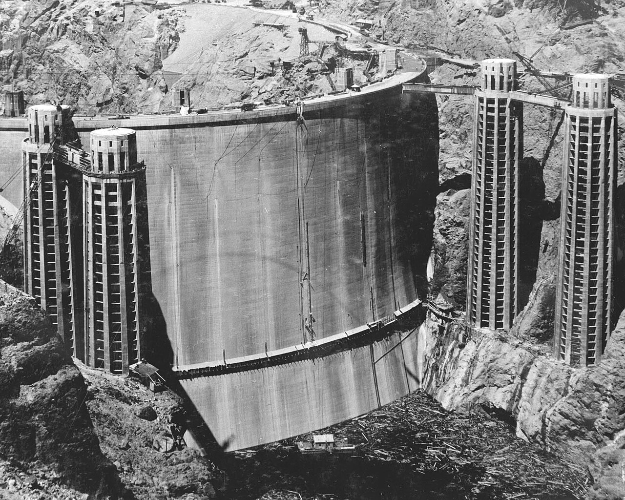 The completed dam rises between its intake towers on dedication day