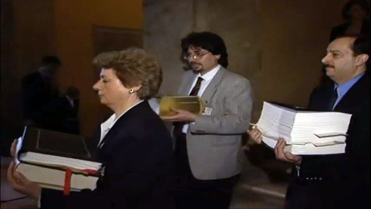 Officials carry bound copies of the treaty into the chamber
