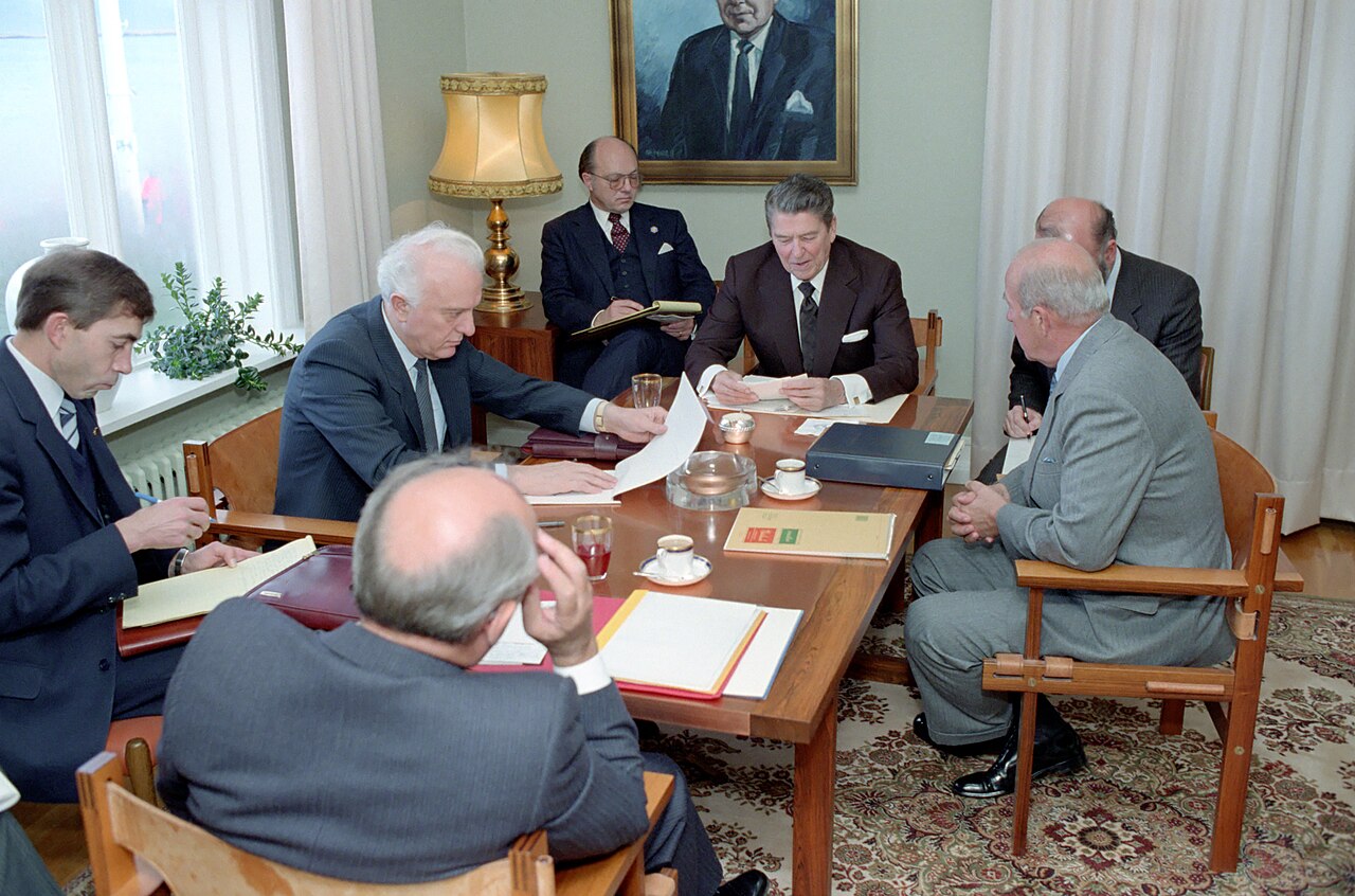 Reagan and Gorbachev sit across a wooden table with aides at Hofdi House
