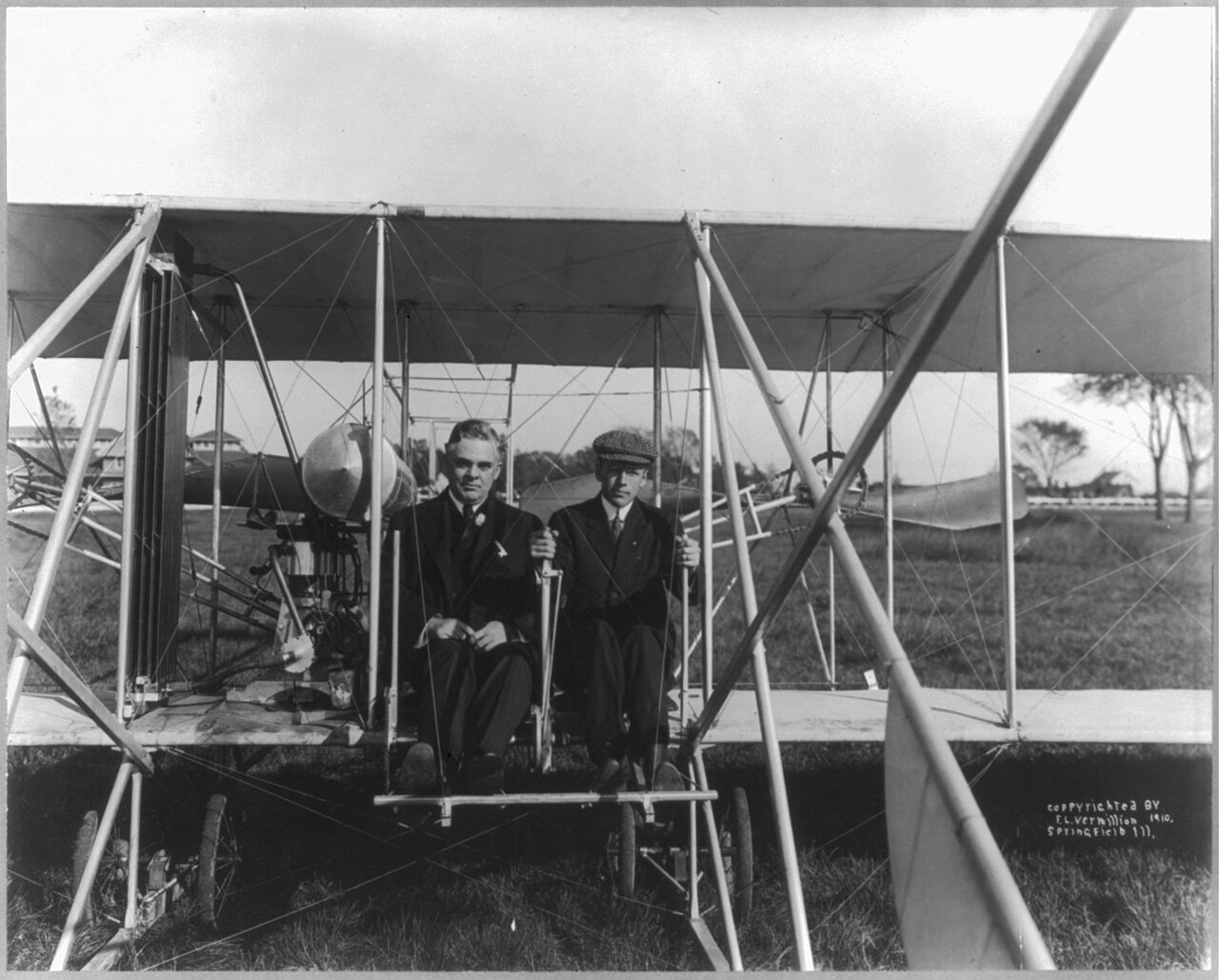 The former president sits beside pilot Arch Hoxsey in the Wright biplane