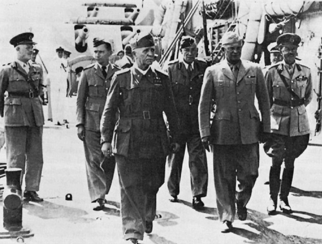 Marshal Badoglio walks with Allied officers aboard a battleship