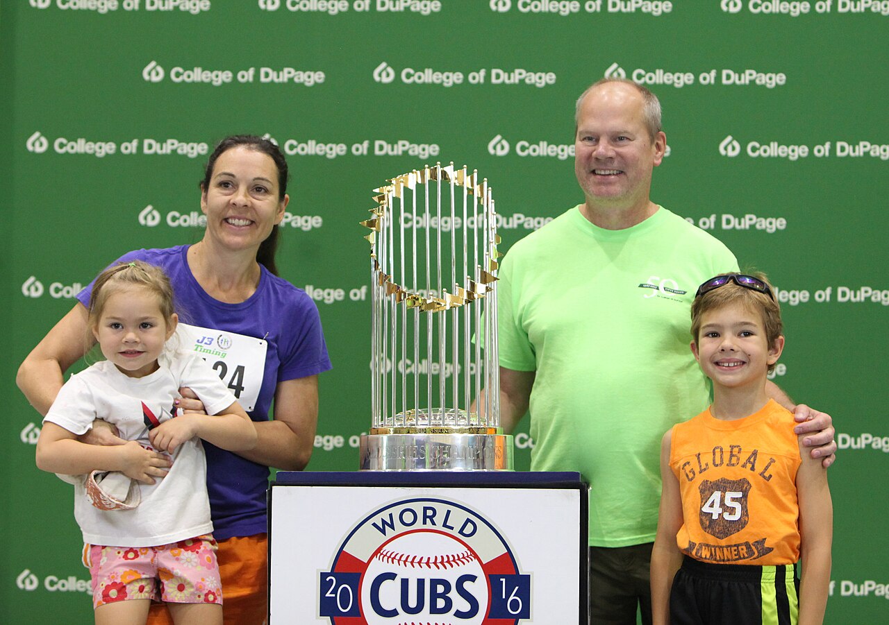The 2016 World Series trophy on display with a family posing beside it