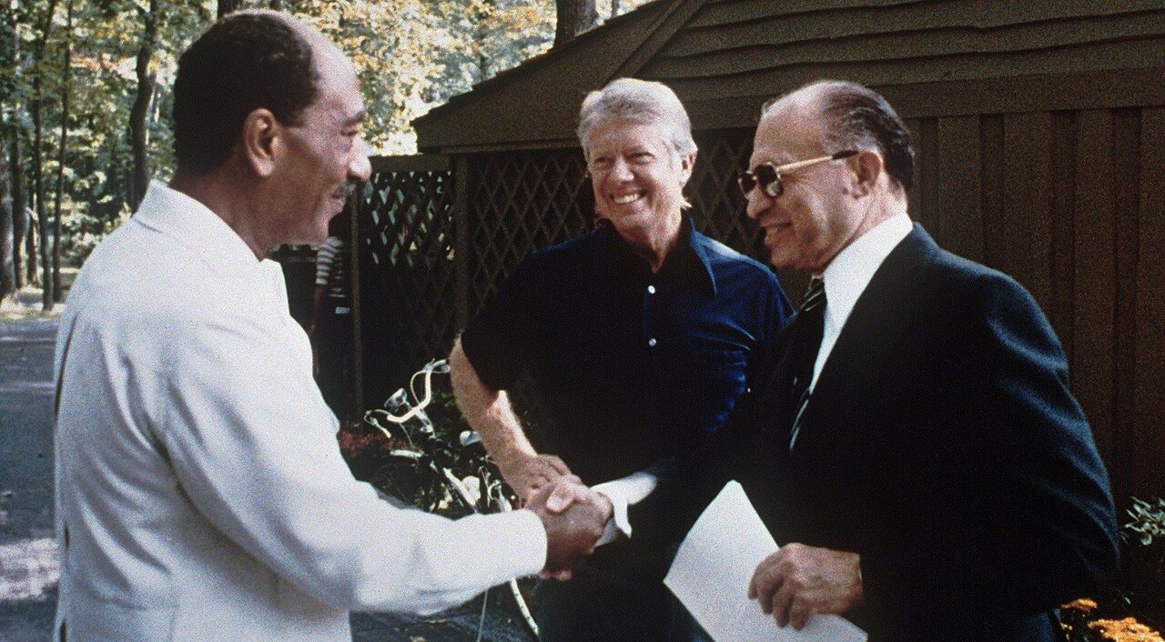 Begin and Sadat shake hands at Camp David as Carter looks on