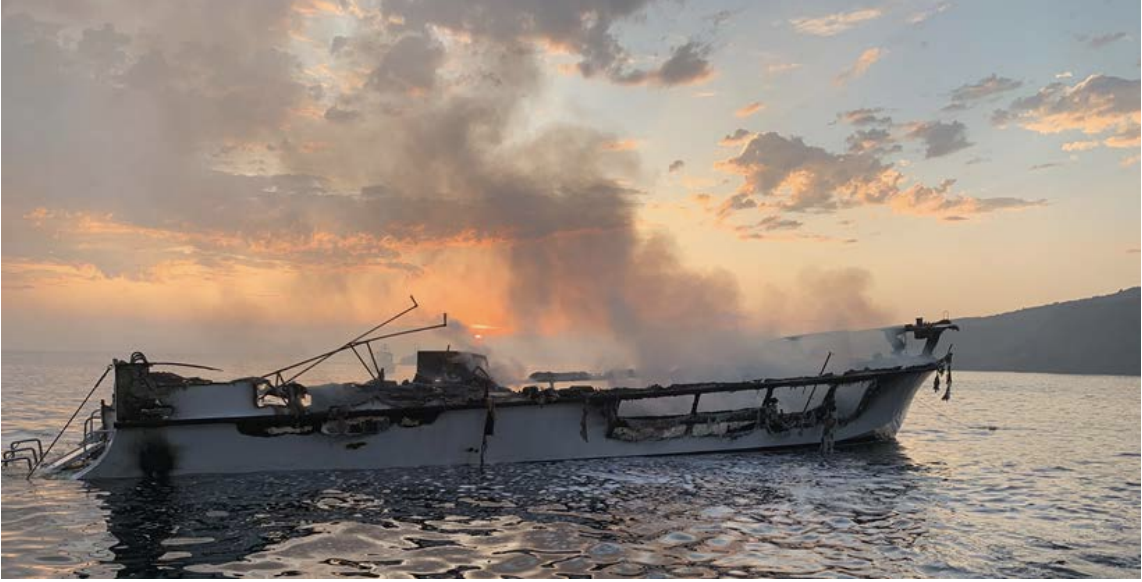 Smoke rises from the burning dive boat at dawn