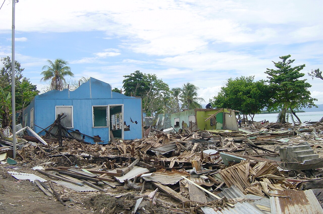 A damaged blue house stands amid debris left by the tsunami