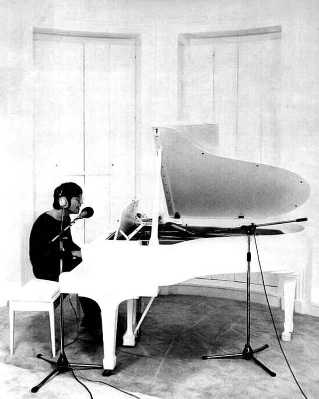 Lennon records at a white grand piano in an all-white room
