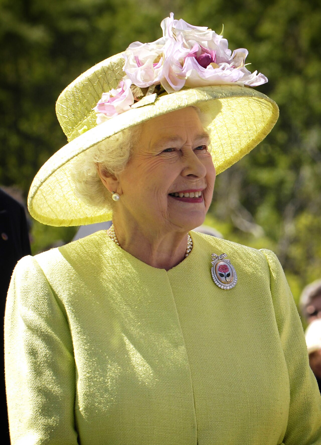 the Queen wears a lime coat and floral hat at a garden party