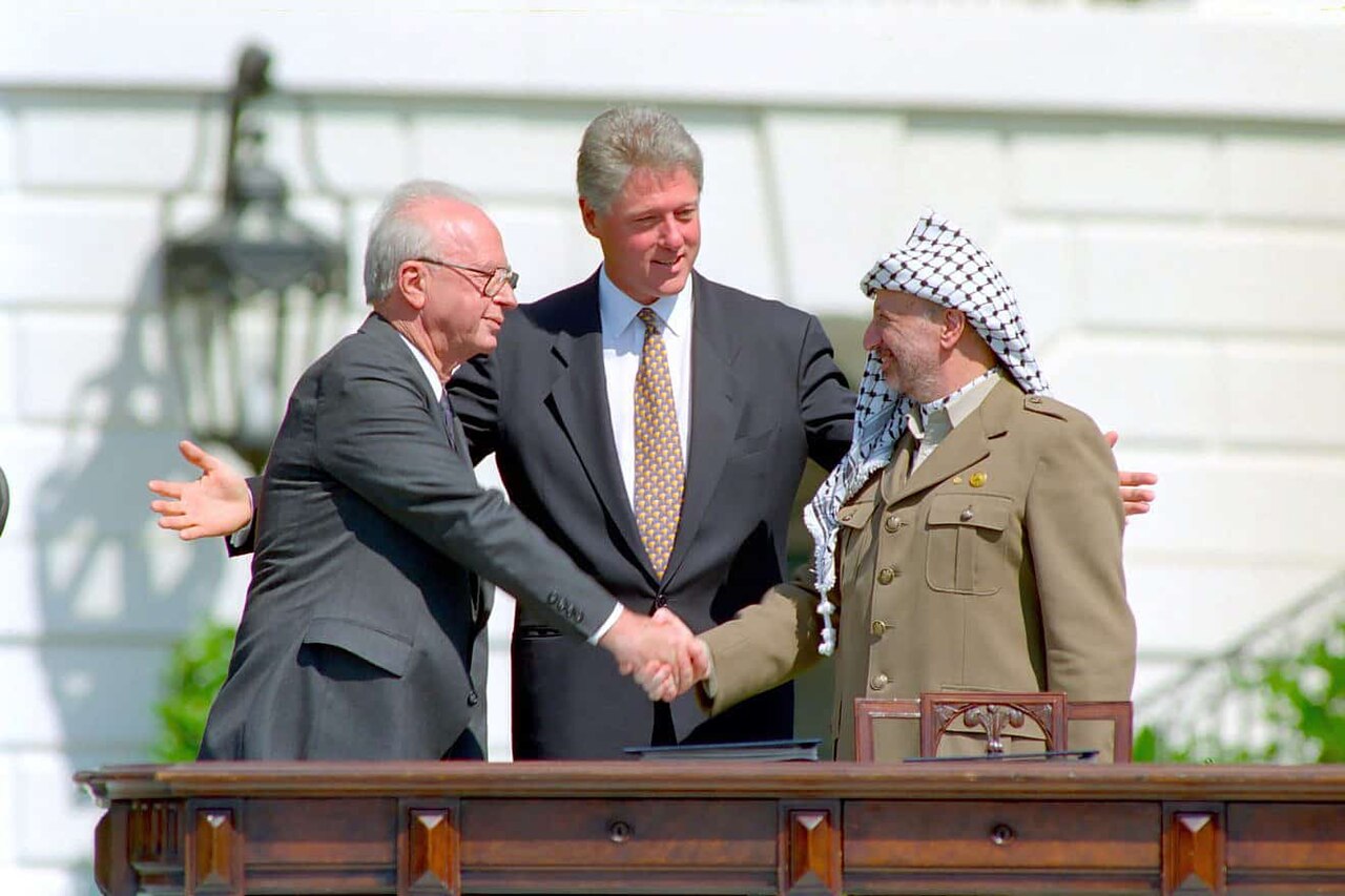 Rabin and Arafat shake hands as Clinton looks on