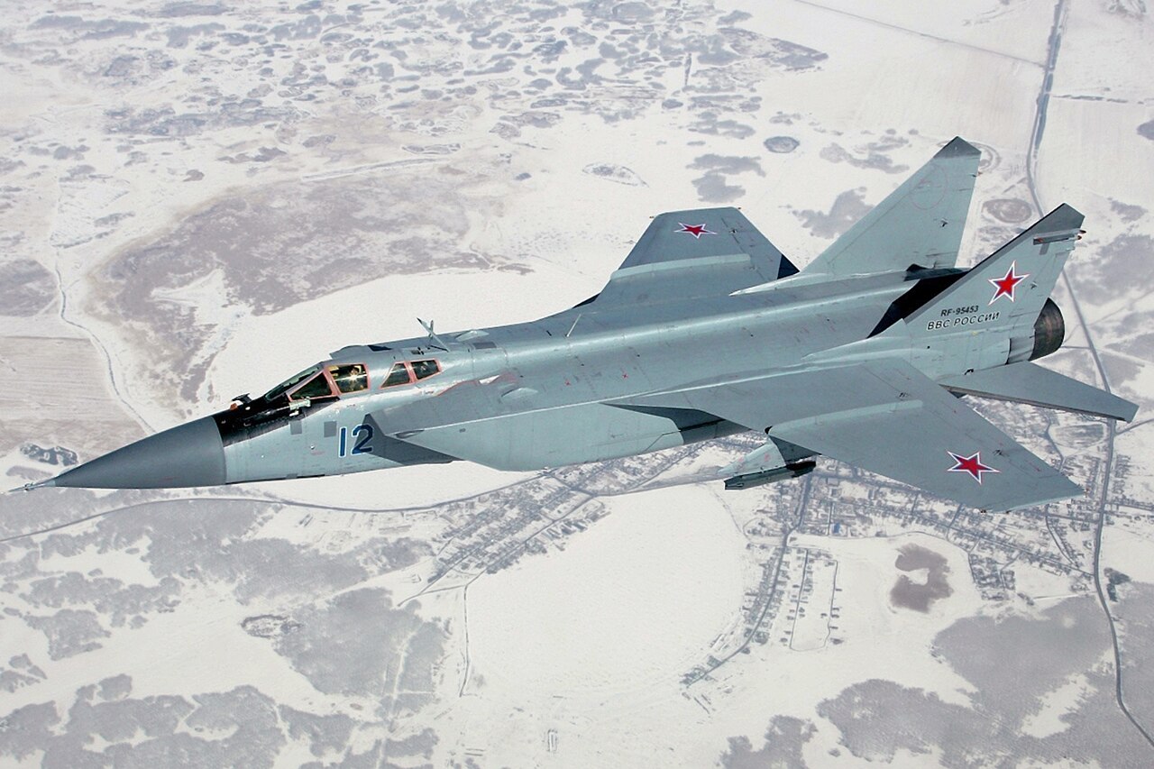 A Soviet MiG-31 interceptor flies over snow-covered terrain